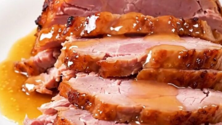 A whole, glazed spiral-cut ham sitting in a slow cooker, glistening with an apricot and Dijon mustard glaze.