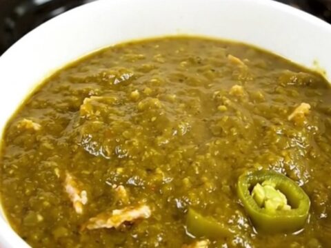 A steaming bowl of green chile ground turkey chili in a white ceramic bowl.
