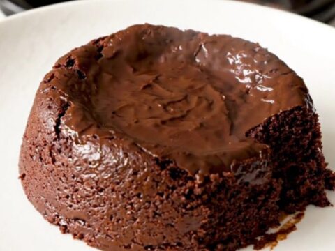 A warm, indulgent slow cooker brownie pudding served in a white bowl with a spoon.
