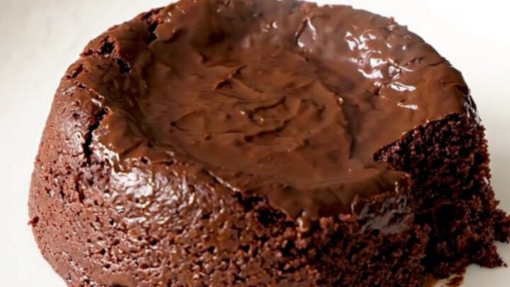 A warm, indulgent slow cooker brownie pudding served in a white bowl with a spoon.