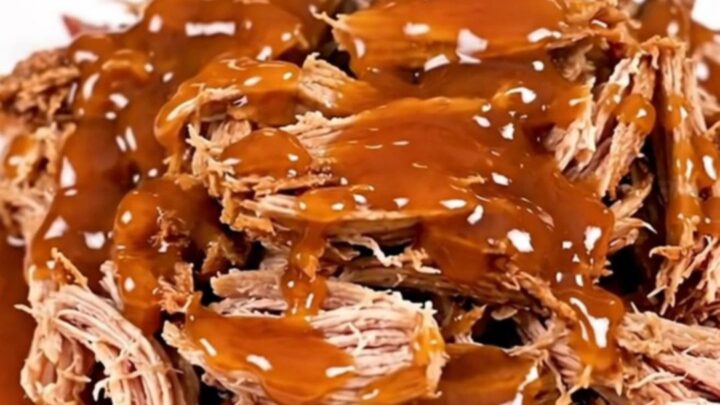 A plate of shredded sweet chili lime pulled pork with a glossy finish on a white plate.