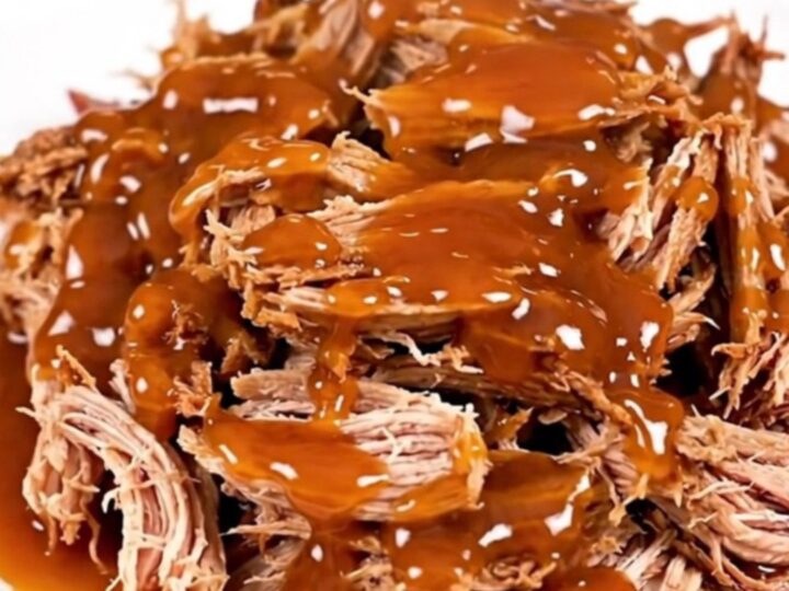 A plate of shredded sweet chili lime pulled pork with a glossy finish on a white plate.