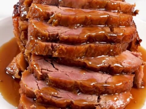 A glistening, glazed spiral-cut ham in a slow cooker, topped with a rich peach and bourbon sauce.