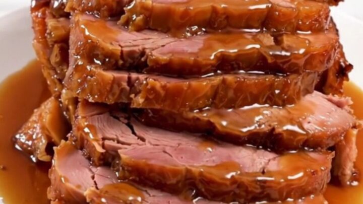 A glistening, glazed spiral-cut ham in a slow cooker, topped with a rich peach and bourbon sauce.