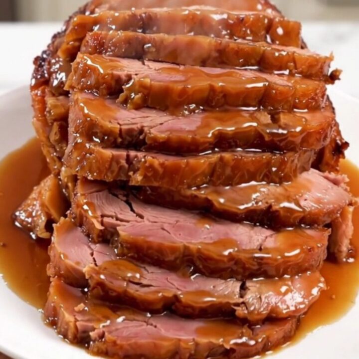 A glistening, glazed spiral-cut ham in a slow cooker, topped with a rich peach and bourbon sauce.