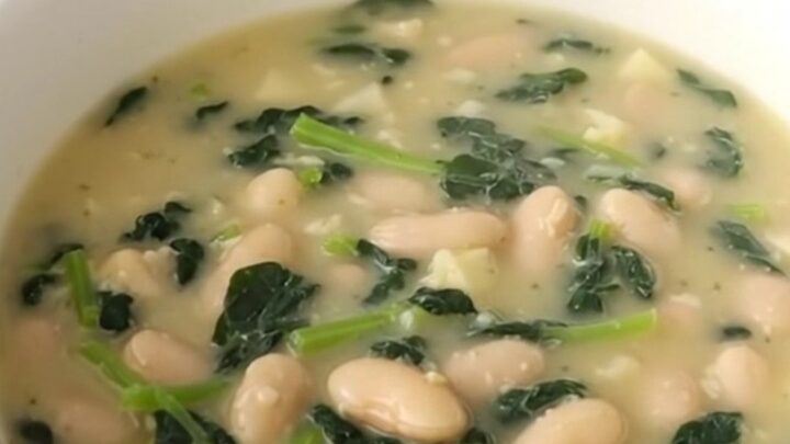 A rustic bowl of creamy white bean and spinach chowder with visible potato cubes and wilted greens.