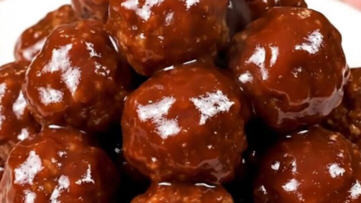 A close-up of glossy barbecue meatballs in a slow cooker, showing the rich, dark sauce and tender texture.