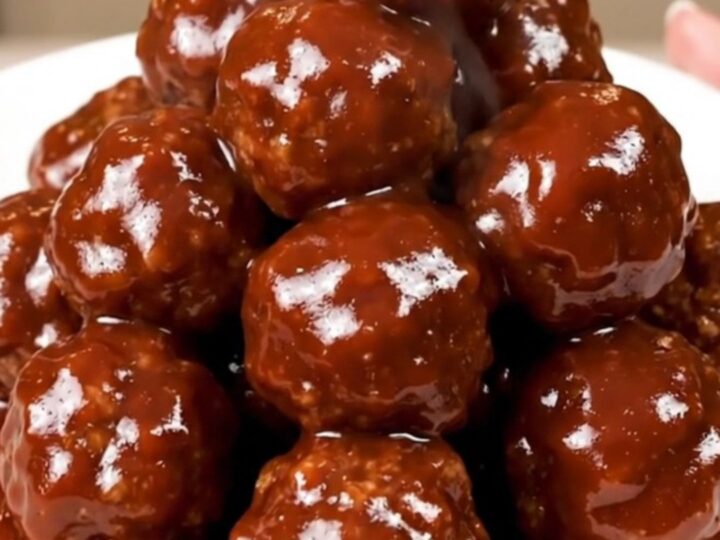 A close-up of glossy barbecue meatballs in a slow cooker, showing the rich, dark sauce and tender texture.