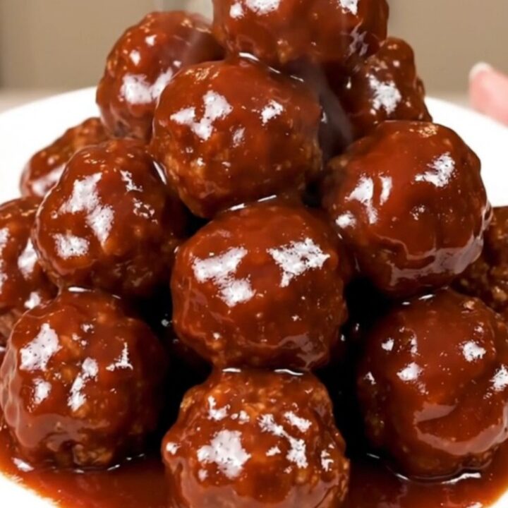 A close-up of glossy barbecue meatballs in a slow cooker, showing the rich, dark sauce and tender texture.