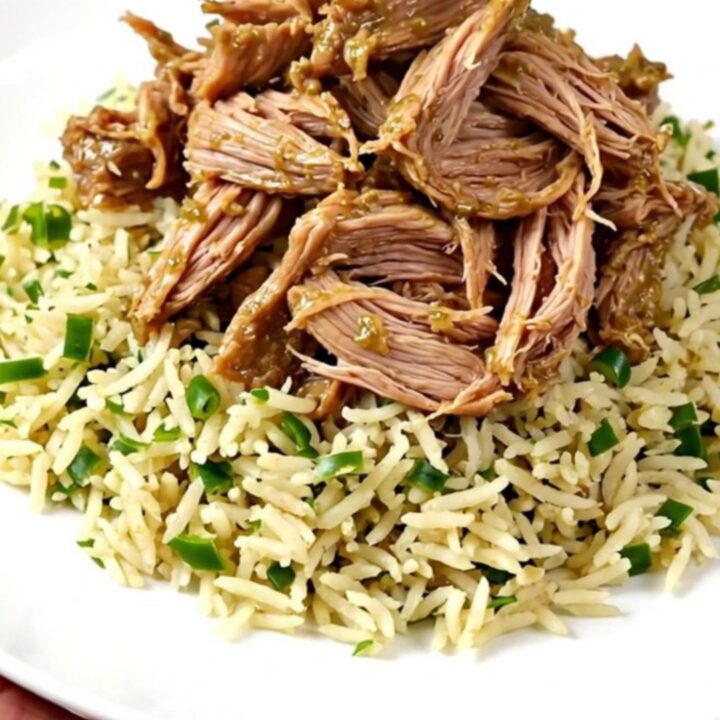A close-up of tender, shredded salsa verde pork chops served over cilantro lime rice on a white plate.