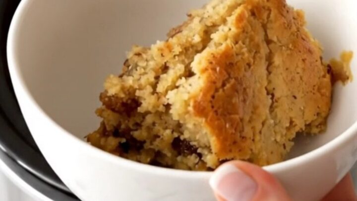 A warm, golden-brown apple butter spice dump cake served in a white bowl with steam rising.