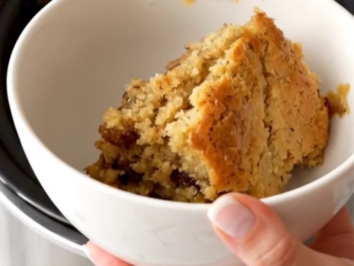 A warm, golden-brown apple butter spice dump cake served in a white bowl with steam rising.