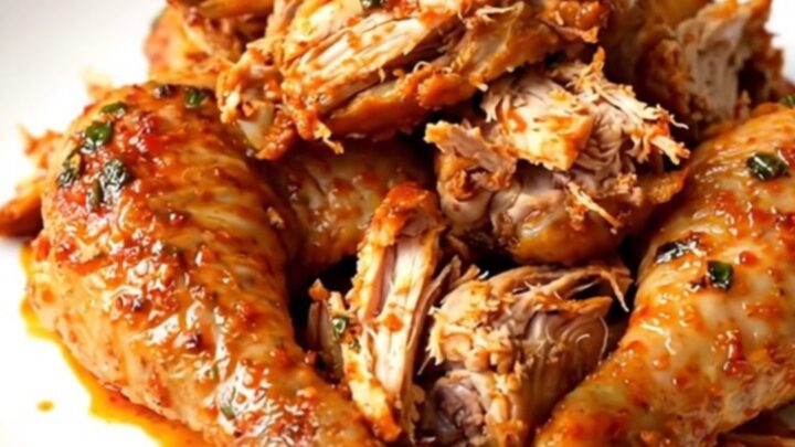 A steaming, shredded whole chicken seasoned with lime and spices on a white plate.