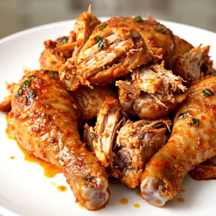 A steaming, shredded whole chicken seasoned with lime and spices on a white plate.
