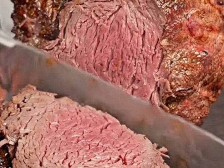 A beautifully crusted standing rib roast freshly carved into thick slices on a dark board