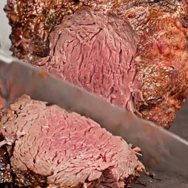 A beautifully crusted standing rib roast freshly carved into thick slices on a dark board
