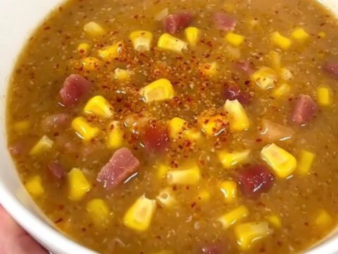 A steaming bowl of creamy chipotle bacon corn chowder garnished with crispy bacon bits.