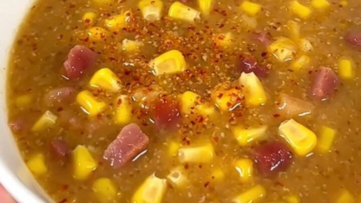 A steaming bowl of creamy chipotle bacon corn chowder garnished with crispy bacon bits.