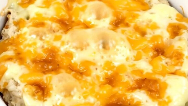 A creamy, melted loaded baked potato dip in a black slow cooker, topped with fresh green onions and cheddar.