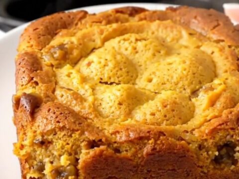 A warm, golden pumpkin gingerbread dump cake served on a white plate with a rustic, home-cooked look.
