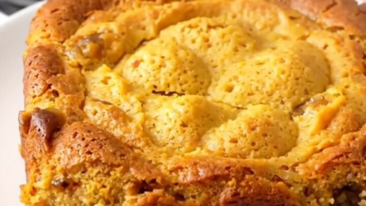 A warm, golden pumpkin gingerbread dump cake served on a white plate with a rustic, home-cooked look.