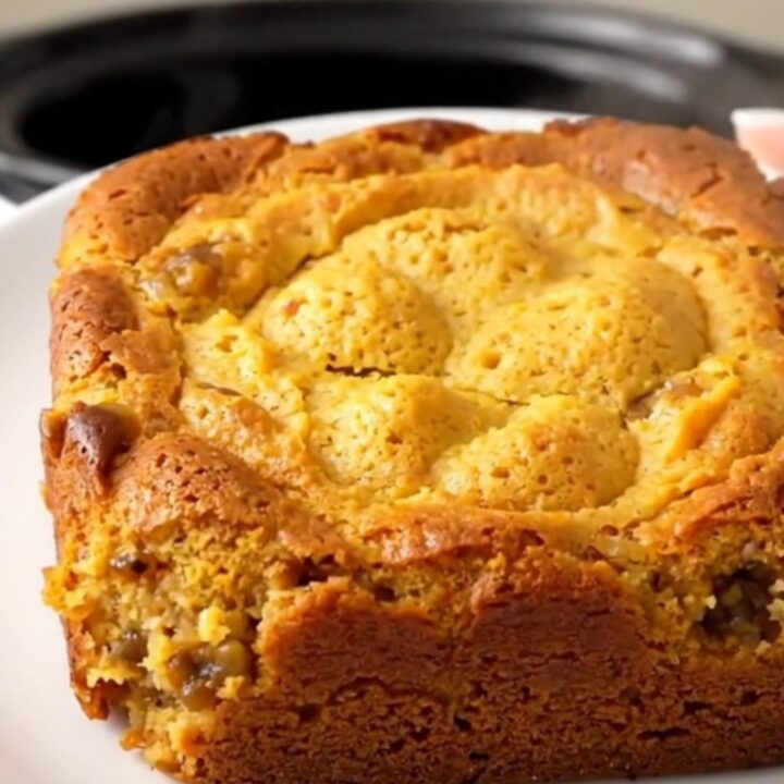 A warm, golden pumpkin gingerbread dump cake served on a white plate with a rustic, home-cooked look.