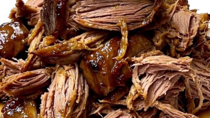 A slow cooker filled with a tender beef chuck roast seasoned with dill pickles and ranch spices on a white countertop.