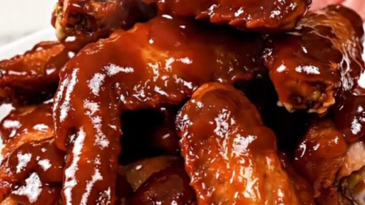 A close overhead view of slow cooker cherry barbecue chicken wings with green onions.