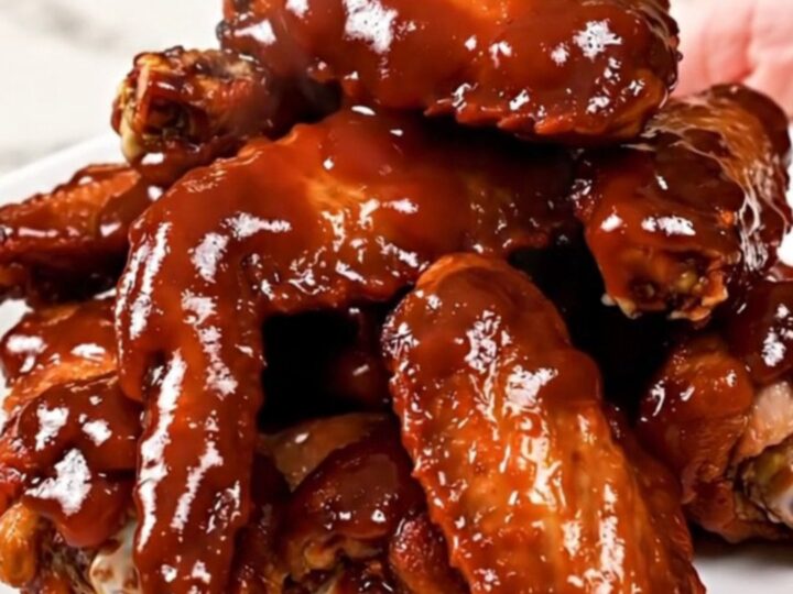 A close overhead view of slow cooker cherry barbecue chicken wings with green onions.