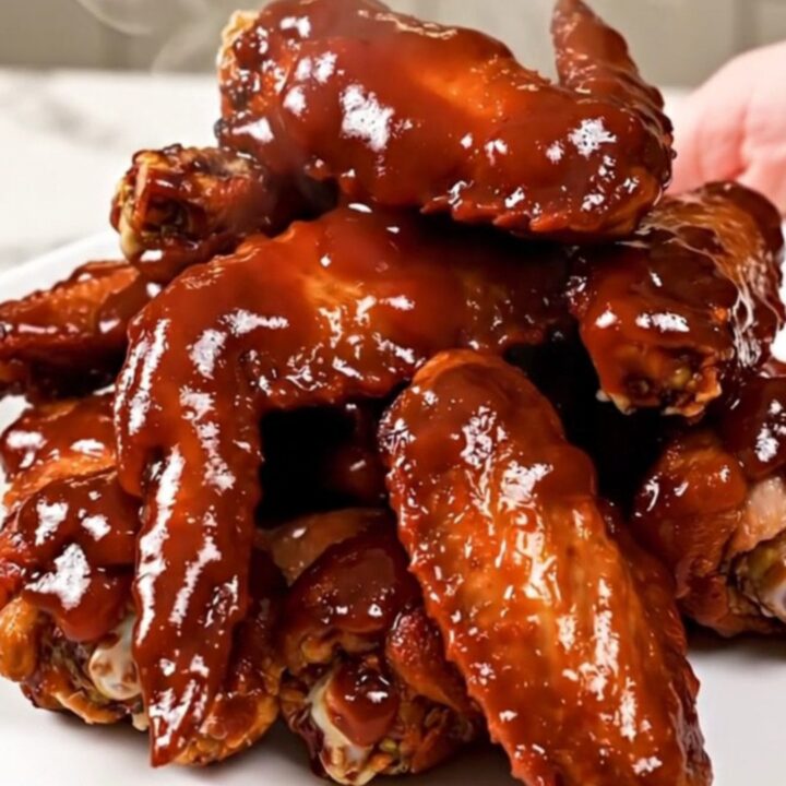 A close overhead view of slow cooker cherry barbecue chicken wings with green onions.