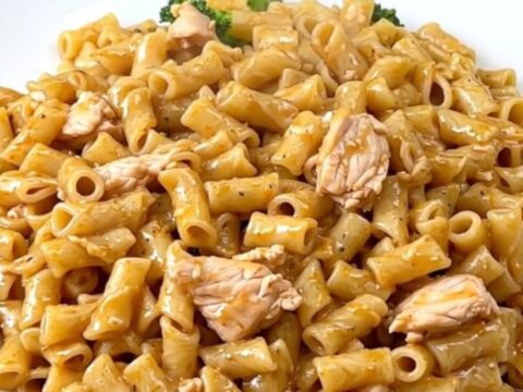 A top-down view of a slow cooker filled with chicken, broccoli, and alfredo sauce ready for cooking.