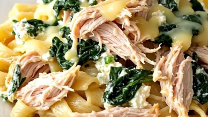 A slow cooker filled with creamy spinach ricotta chicken garnished with fresh herbs on a quartz countertop.