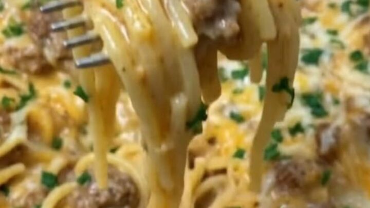A warm skillet filled with creamy cheddar beef spaghetti, showing a fork lifting cheesy noodles.
