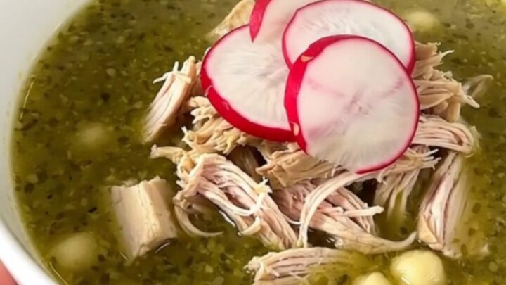 A bowl of Crockpot Chicken Pozole Verde topped with fresh radish slices, viewed from a slightly elevated angle.
