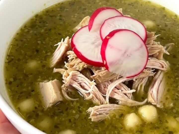 A bowl of Crockpot Chicken Pozole Verde topped with fresh radish slices, viewed from a slightly elevated angle.