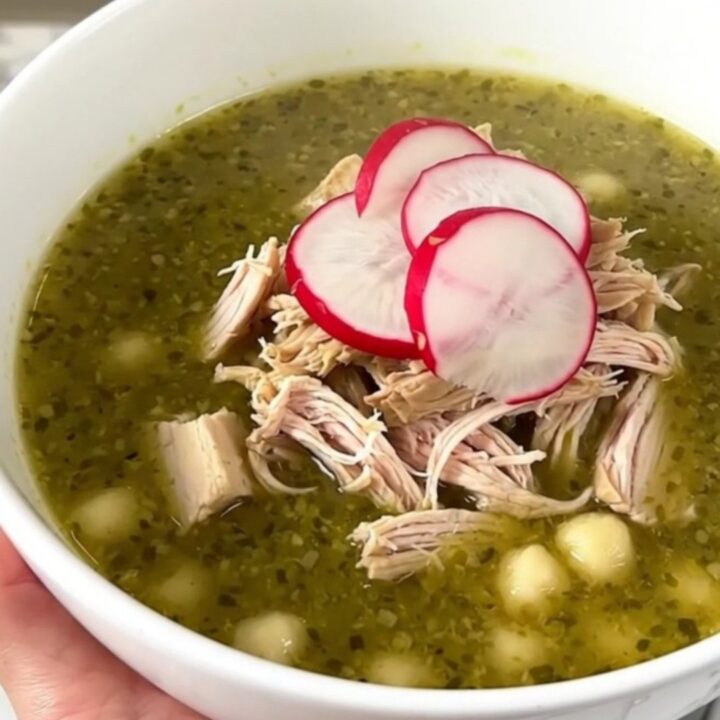 A bowl of Crockpot Chicken Pozole Verde topped with fresh radish slices, viewed from a slightly elevated angle.