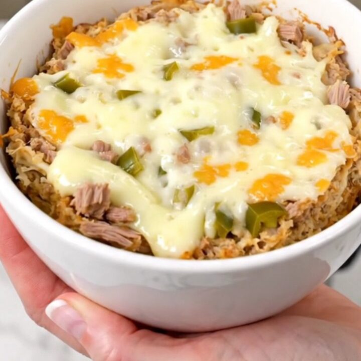 A top-down view of a creamy pulled pork dip in a slow cooker topped with melted cheese and green chiles.