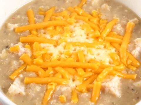 A steaming bowl of creamy cheddar ale bacon chowder topped with melted cheddar cheese.
