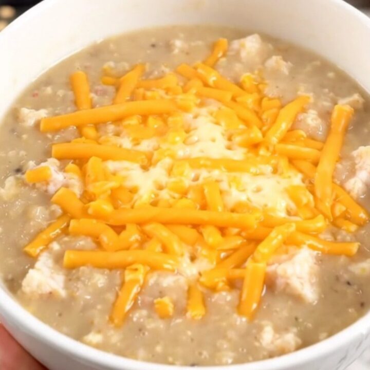 A steaming bowl of creamy cheddar ale bacon chowder topped with melted cheddar cheese.
