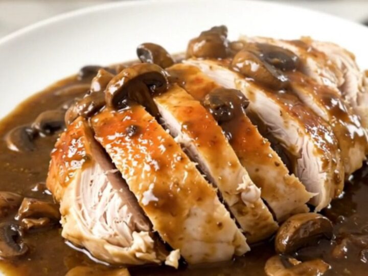 A whole chicken cooked in a slow cooker, smothered in a rich, creamy mushroom sauce with visible mushroom slices.