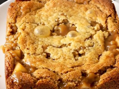 A warm, golden-brown butterscotch apple dump cake served in a white bowl.