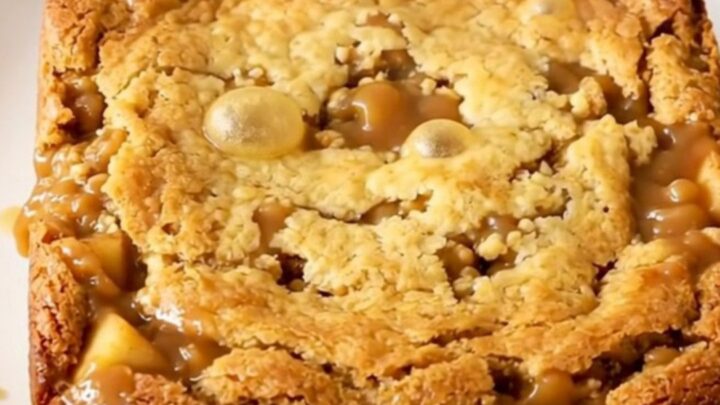 A warm, golden-brown butterscotch apple dump cake served in a white bowl.