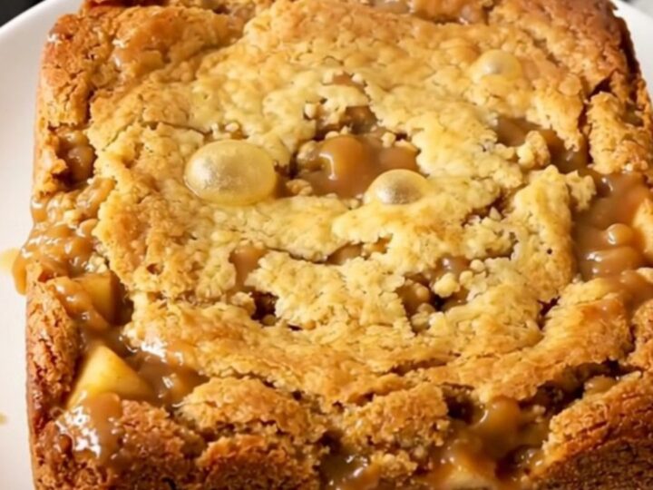 A warm, golden-brown butterscotch apple dump cake served in a white bowl.