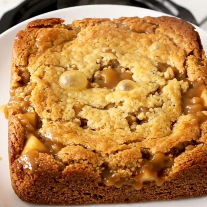 A warm, golden-brown butterscotch apple dump cake served in a white bowl.