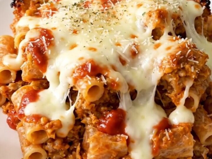A top-down view of a black slow cooker filled with meatballs, peppers, and marinara sauce on a white quartz countertop.