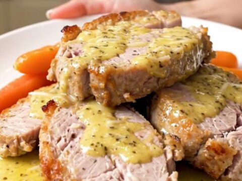 A top-down view of garlic parmesan pork tenderloin with glazed carrots in a slow cooker.