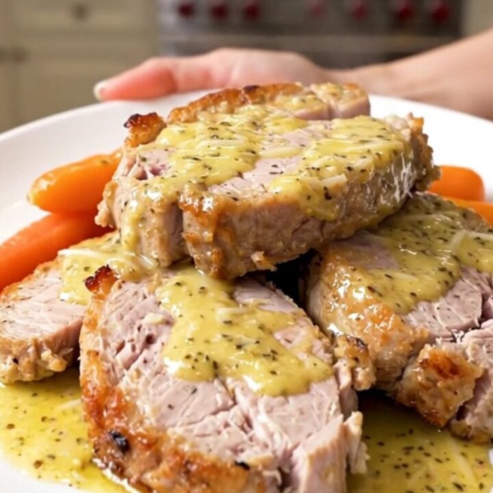 A top-down view of garlic parmesan pork tenderloin with glazed carrots in a slow cooker.