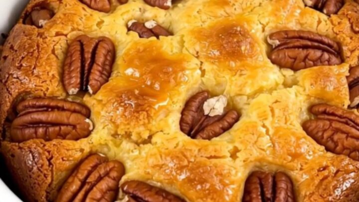 A warm, golden sweet potato pecan dump cake served in a white bowl, showing a bubbly, textured top.