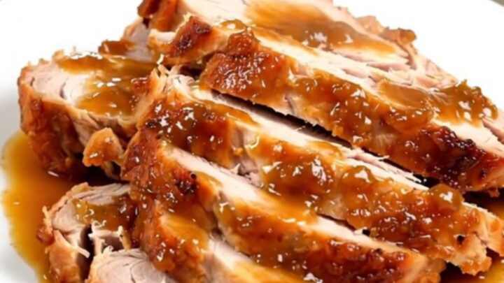 A succulent, sliced turkey breast with a glossy apple glaze on a white plate.