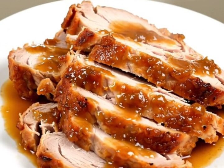 A succulent, sliced turkey breast with a glossy apple glaze on a white plate.